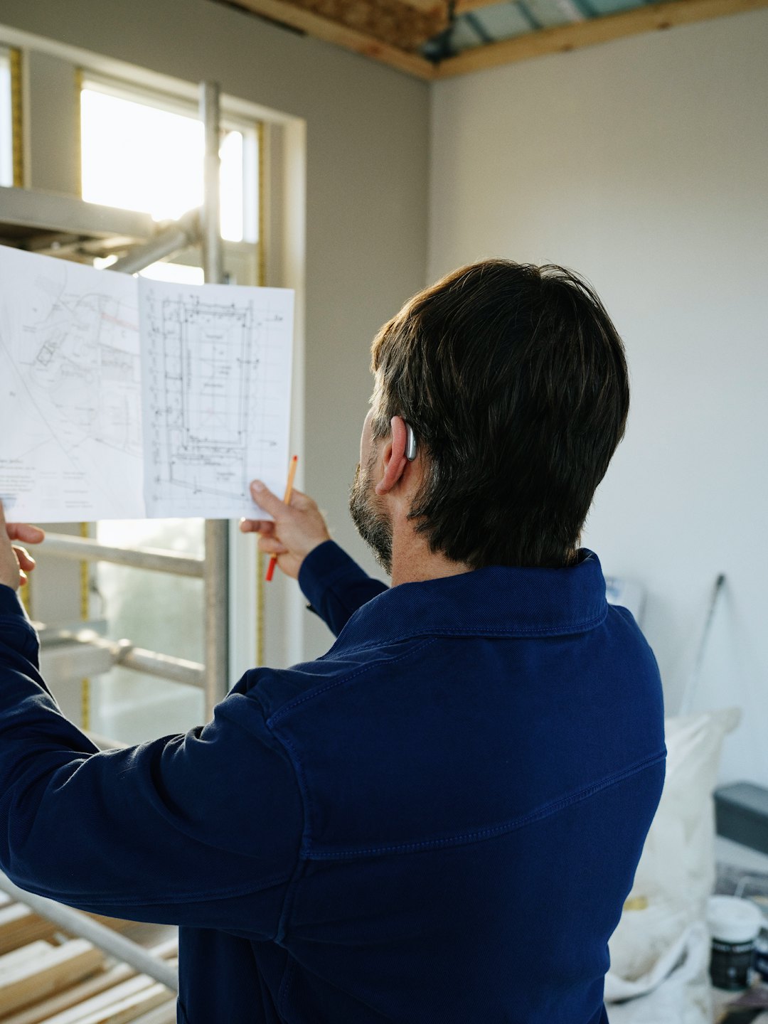 Obrero de la construcción revisa planos en una habitación sin terminar.