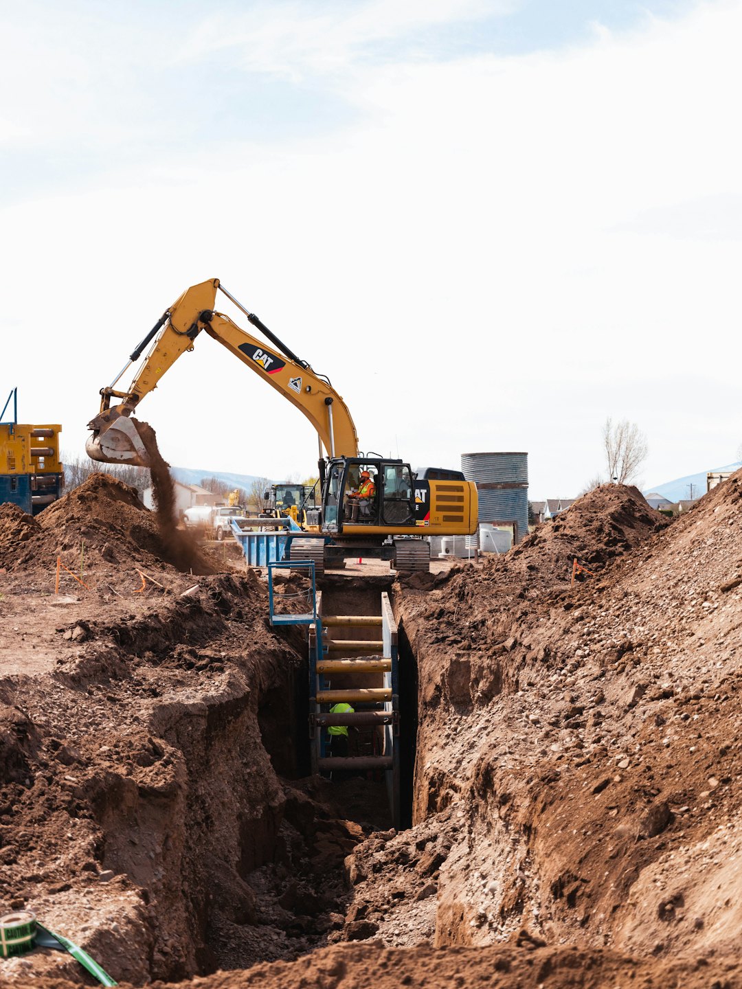 Obrero de la construcción opera excavadora cavando tierra en una zanja.